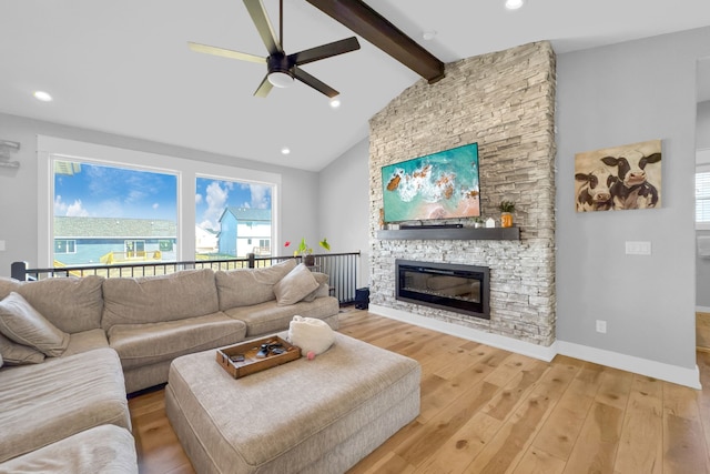 living room featuring ceiling fan, light hardwood / wood-style floors, lofted ceiling with beams, and a stone fireplace