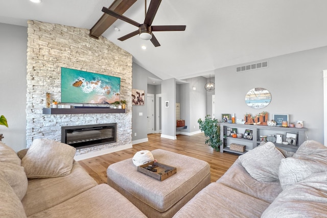 living room with hardwood / wood-style floors, lofted ceiling with beams, a stone fireplace, and ceiling fan