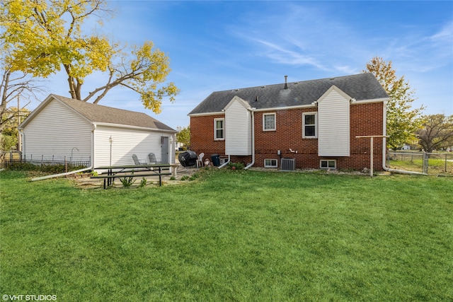 rear view of house with central air condition unit and a lawn