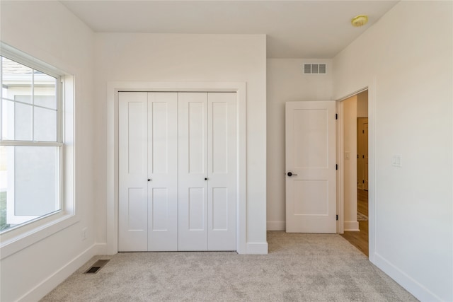 unfurnished bedroom with light colored carpet and a closet