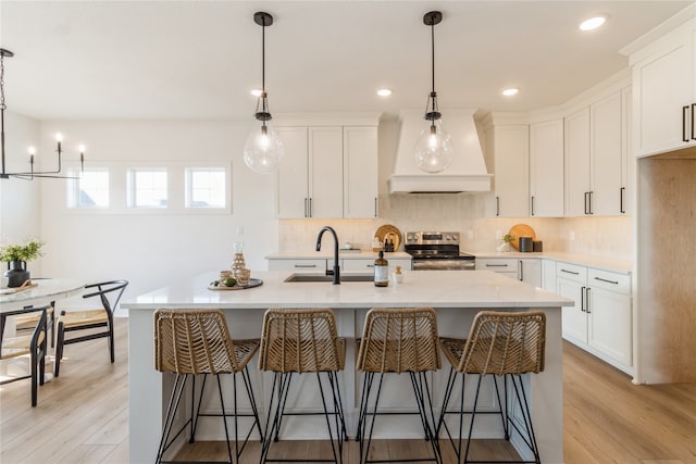 kitchen with a center island with sink, white cabinetry, light hardwood / wood-style flooring, electric stove, and sink