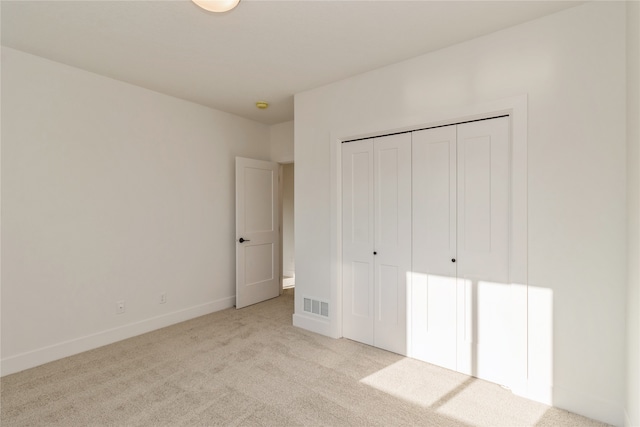 unfurnished bedroom with light carpet and a closet