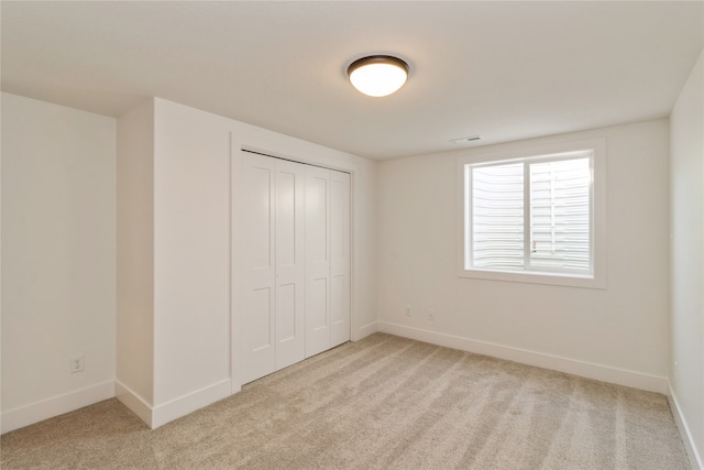 unfurnished bedroom featuring light carpet and a closet