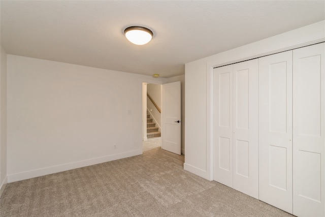 unfurnished bedroom featuring light colored carpet and a closet