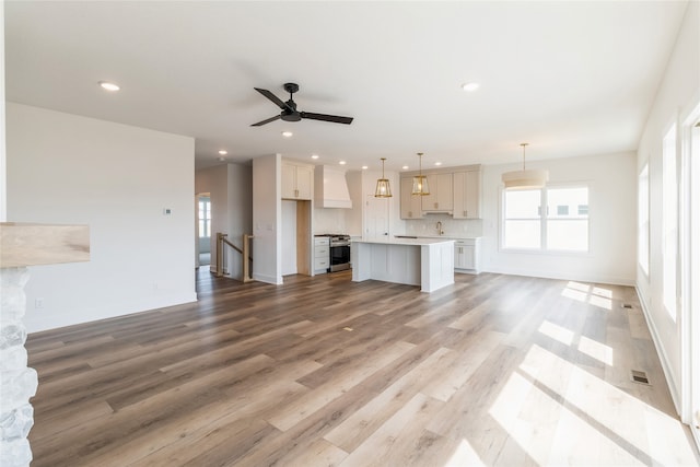 unfurnished living room featuring ceiling fan, wood-type flooring, and sink