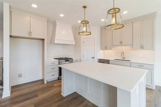 kitchen featuring appliances with stainless steel finishes, wood-type flooring, a center island, pendant lighting, and premium range hood