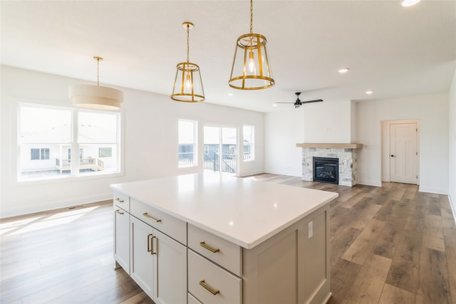 kitchen with a kitchen island, ceiling fan, pendant lighting, white cabinets, and hardwood / wood-style flooring