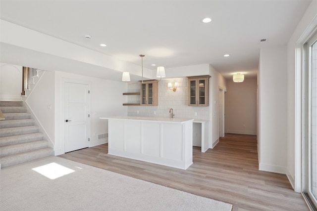 kitchen with light hardwood / wood-style floors, decorative backsplash, sink, and pendant lighting