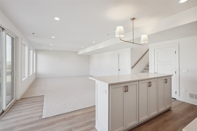 kitchen with white cabinetry, light hardwood / wood-style floors, pendant lighting, and a kitchen island