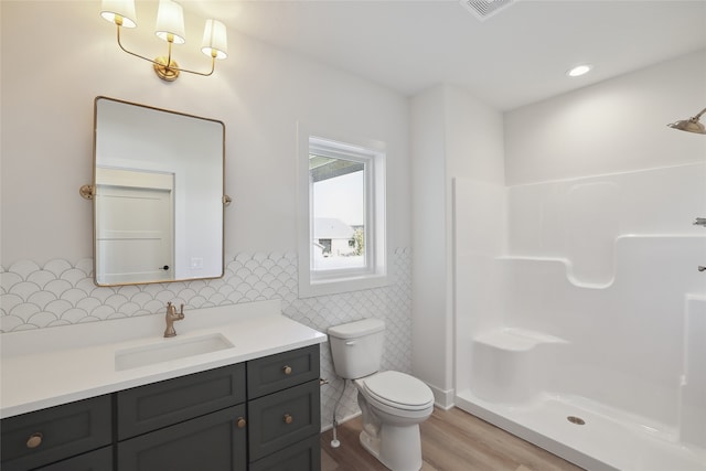 bathroom with wood-type flooring, toilet, tile walls, vanity, and a shower