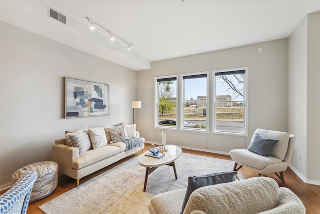 living area with visible vents, baseboards, and wood finished floors