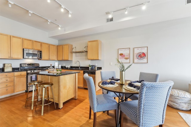 kitchen with light brown cabinets, stainless steel appliances, a sink, and light wood-style flooring