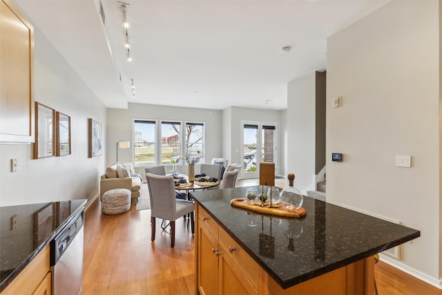 kitchen featuring dark stone counters, dishwasher, a kitchen island, and light hardwood / wood-style flooring