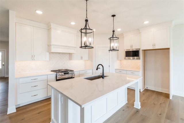 kitchen with white cabinetry, appliances with stainless steel finishes, sink, and an island with sink