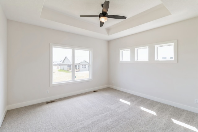 spare room featuring ceiling fan, a raised ceiling, and carpet flooring