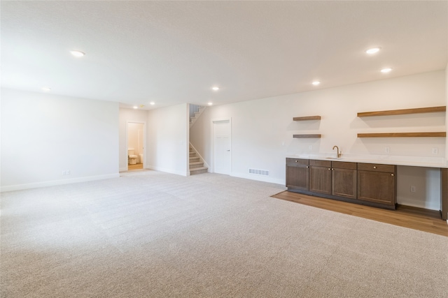 unfurnished living room with light colored carpet and sink