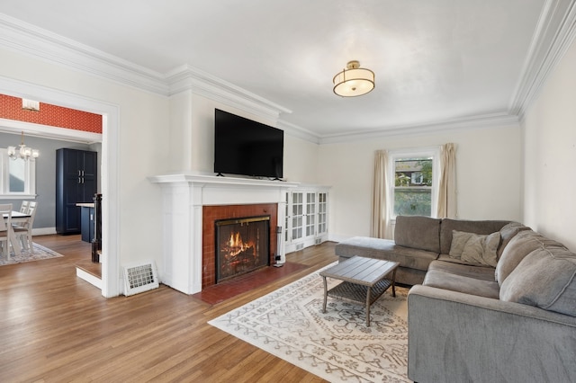 living room with crown molding, a notable chandelier, and wood-type flooring