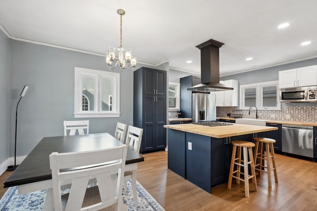 kitchen with light hardwood / wood-style flooring, stainless steel appliances, backsplash, a center island, and butcher block countertops