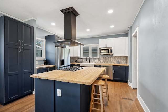 kitchen with island range hood, a breakfast bar area, wood counters, appliances with stainless steel finishes, and light hardwood / wood-style floors