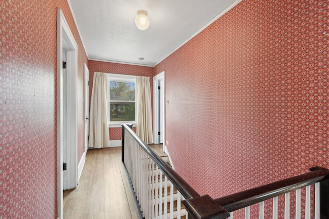 corridor with ornamental molding and light hardwood / wood-style flooring