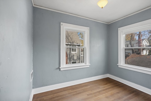 unfurnished room with ornamental molding, wood-type flooring, and plenty of natural light