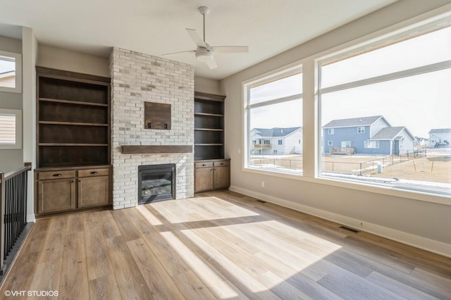 unfurnished living room featuring light wood-style flooring, a fireplace, baseboards, and a residential view