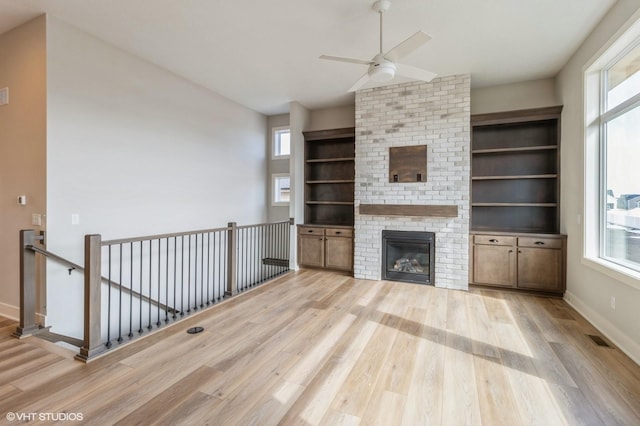 unfurnished living room with light wood finished floors, plenty of natural light, and a fireplace