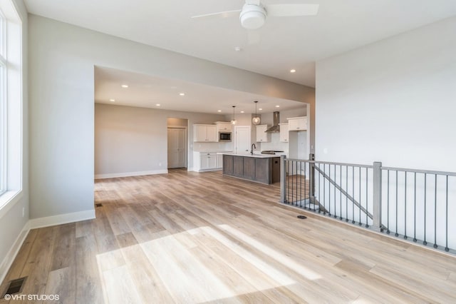 unfurnished living room featuring baseboards, visible vents, light wood-style floors, a sink, and recessed lighting