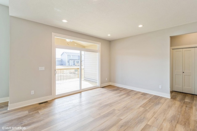 empty room featuring light wood-type flooring, baseboards, visible vents, and recessed lighting