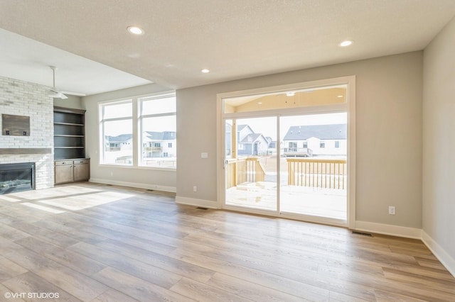 unfurnished living room featuring light wood-type flooring, a fireplace, and baseboards