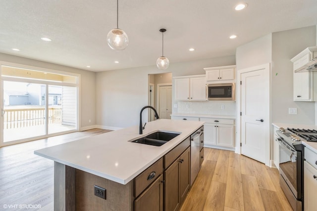 kitchen with light wood-style flooring, a sink, range with gas stovetop, built in microwave, and dishwasher