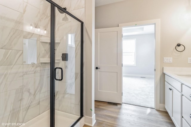 bathroom with a shower stall, baseboards, wood finished floors, and vanity