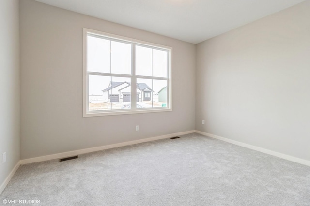 carpeted spare room with visible vents and baseboards