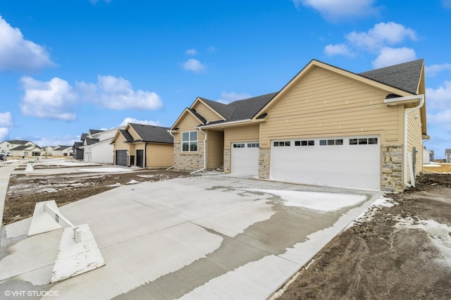 ranch-style house featuring a garage, driveway, a shingled roof, stone siding, and a residential view