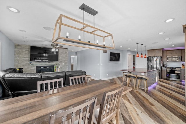 dining space featuring light hardwood / wood-style flooring, a fireplace, and ceiling fan