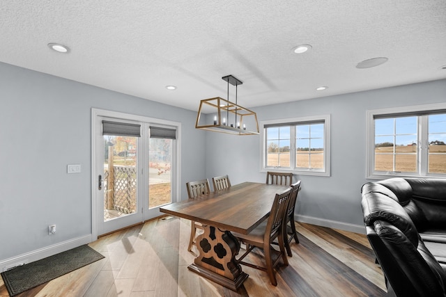 dining room featuring a notable chandelier, a textured ceiling, and light wood-type flooring