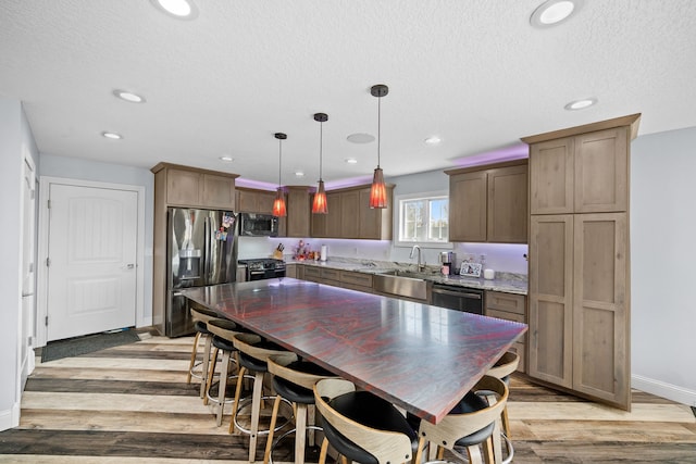 kitchen featuring appliances with stainless steel finishes, light hardwood / wood-style flooring, pendant lighting, and a kitchen island