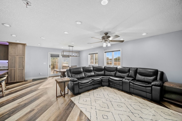 living room featuring a textured ceiling, light wood-type flooring, and ceiling fan