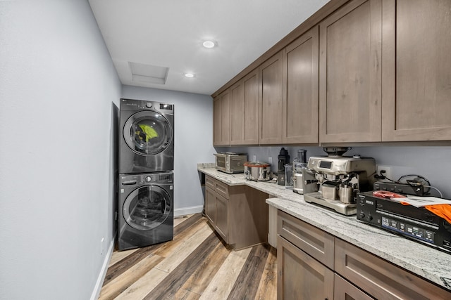 clothes washing area featuring light wood-type flooring and stacked washer and clothes dryer