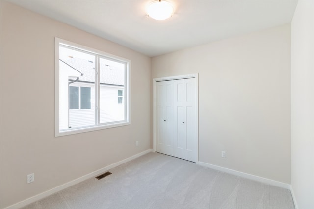 unfurnished bedroom with light carpet and a closet