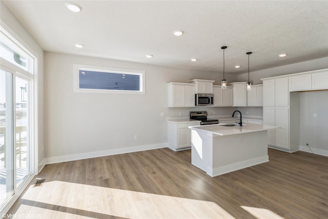 kitchen featuring decorative light fixtures, stainless steel appliances, light countertops, white cabinets, and a kitchen island with sink