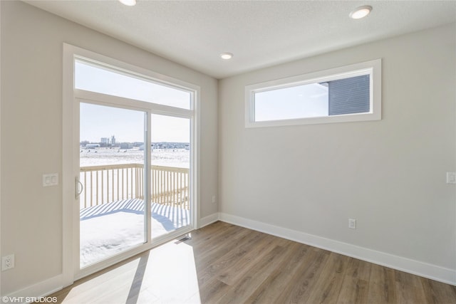 unfurnished room featuring a textured ceiling, light wood-style floors, visible vents, and baseboards