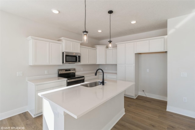 kitchen with stainless steel appliances, light countertops, a kitchen island with sink, white cabinets, and a sink