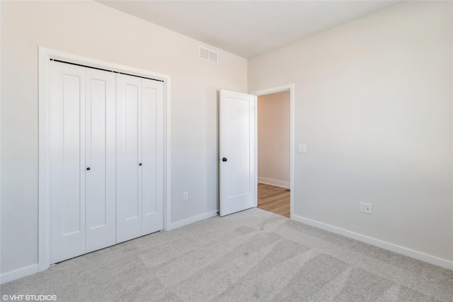 unfurnished bedroom with light carpet, baseboards, visible vents, and a closet