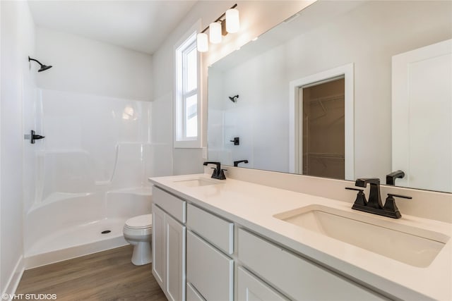 bathroom with a stall shower, a sink, and wood finished floors