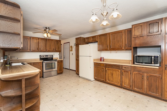 kitchen with stainless steel appliances, sink, pendant lighting, a textured ceiling, and ceiling fan with notable chandelier