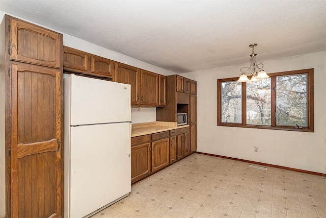 kitchen featuring an inviting chandelier, a textured ceiling, white fridge, and hanging light fixtures