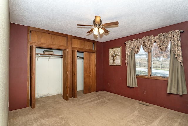 unfurnished bedroom featuring light carpet, a closet, a textured ceiling, and ceiling fan