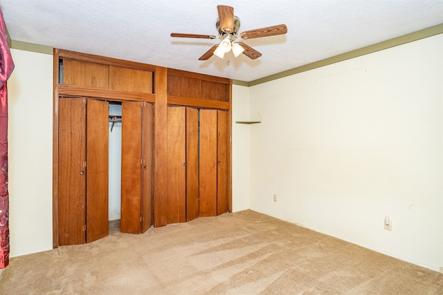 unfurnished bedroom featuring light carpet, a textured ceiling, a closet, and ceiling fan