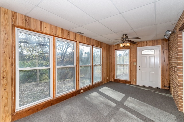 unfurnished sunroom with a wealth of natural light, a drop ceiling, and ceiling fan